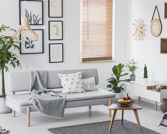 Houten jaloezieën raambekleding scandinavisch interieur woonkamer grijze bank slanke poten koffietafel TV-meubel botanische posters
